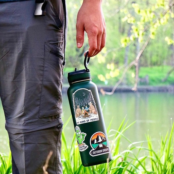 A man holding a bottle with three stickers on it 
